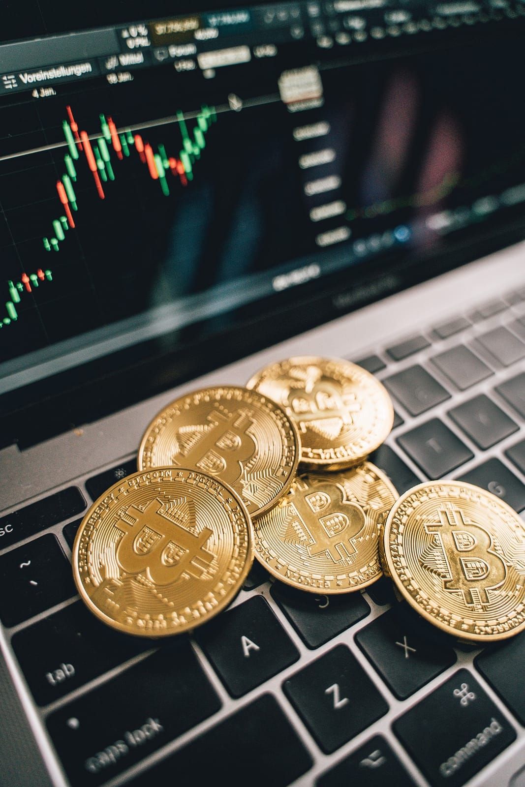 Bitcoin coins in front of a laptop showing a price chart